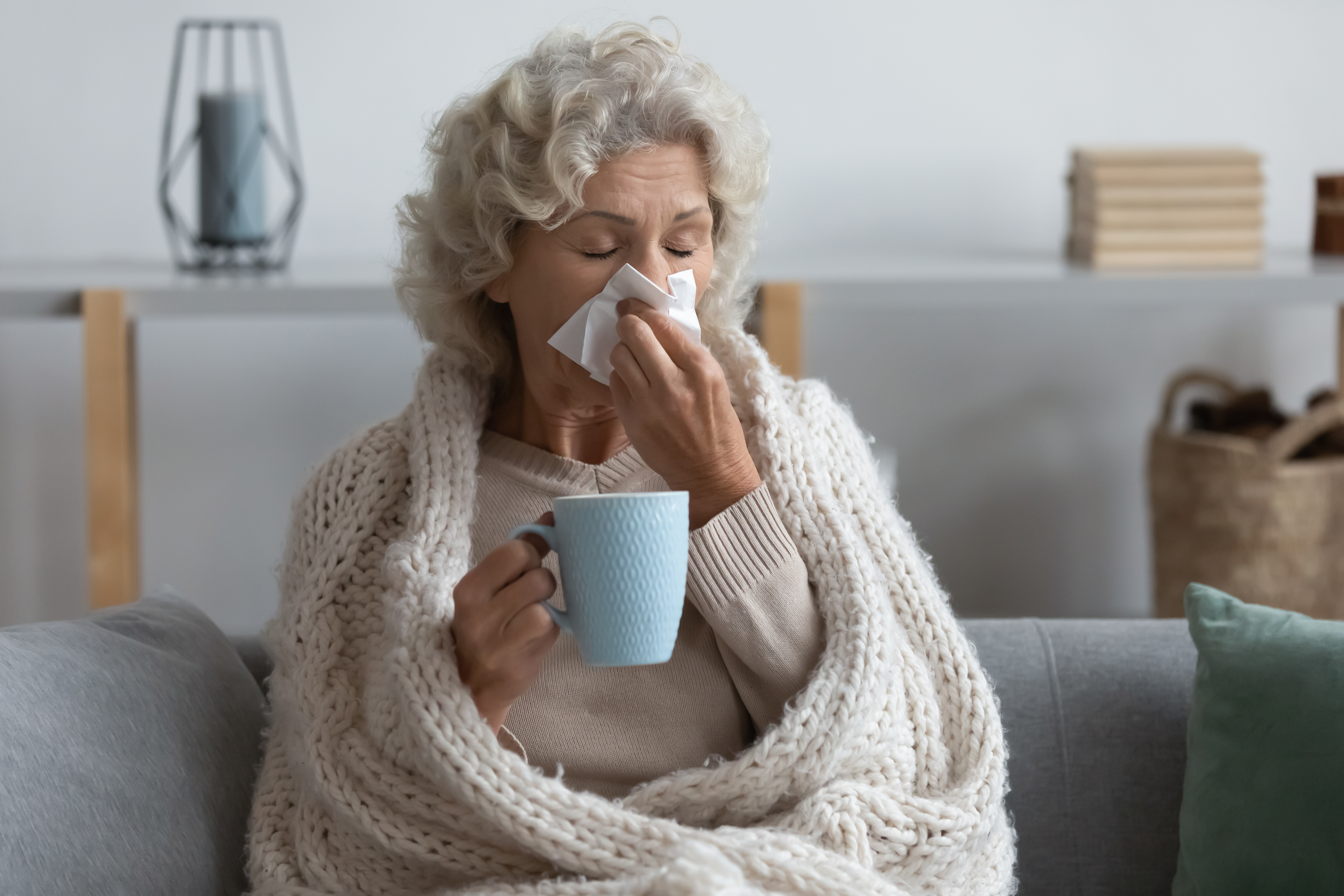 Woman sick with tissues and a cup of tea